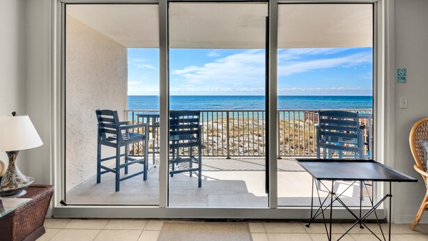 A balcony with a table and chairs, overlooking a beach and the ocean. - Starboard Village 423 (Pensacola Beach)