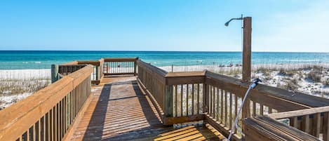 A wooden boardwalk leading to a beach with a clear view of the ocean.