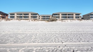 A beachfront hotel with multiple floors, balconies, and a wooden walkway leading to the beach. - Starboard Village 411 (Pensacola Beach)