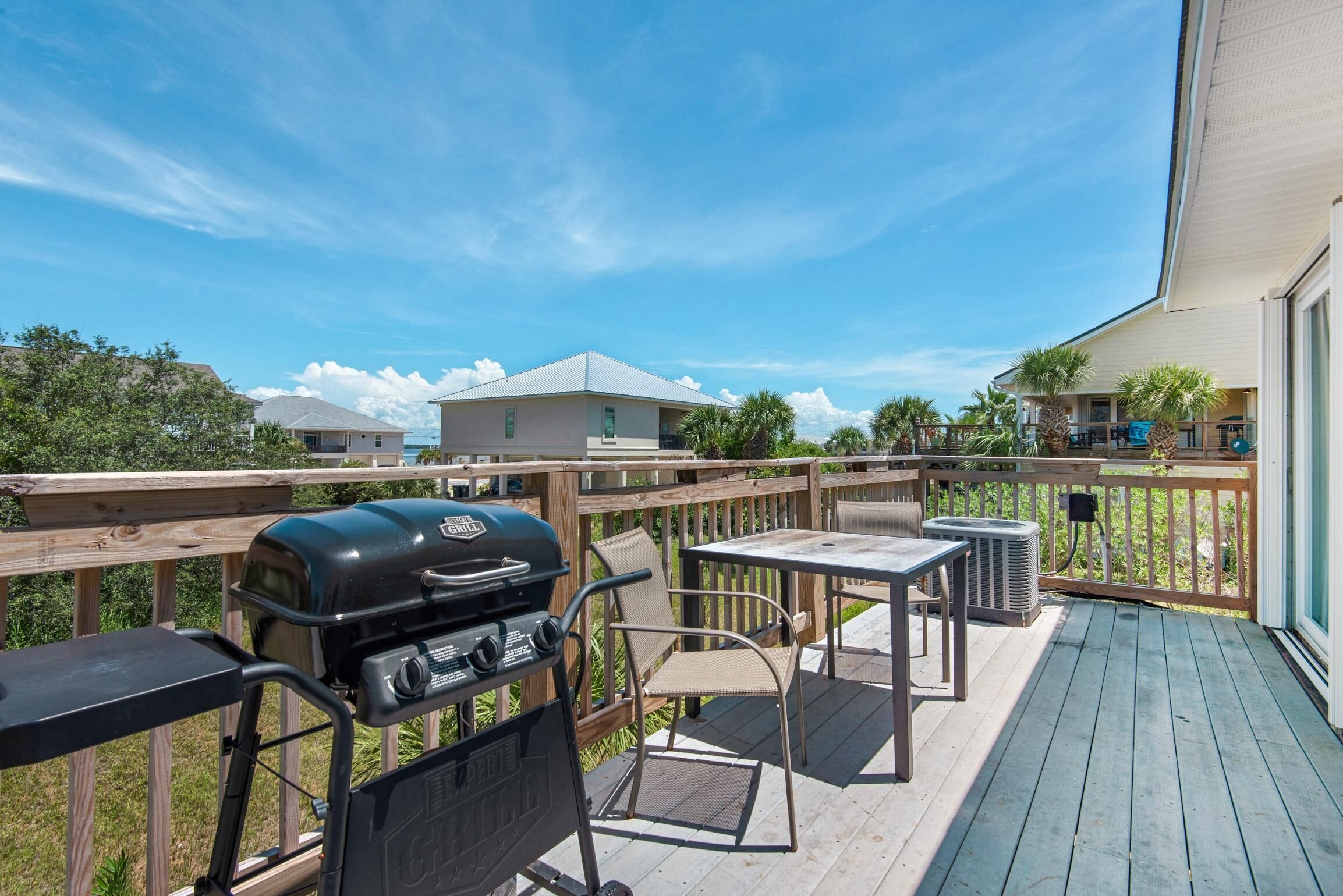 A wooden deck with a grill, a table, and chairs.
