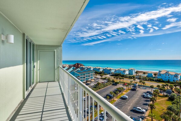 A balcony with a view of a coastal area, including a beach and several buildings.
