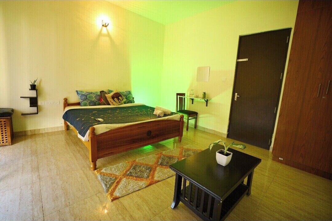 Una camera da letto con un letto, un comodino, una sedia, una porta e una mensola a parete.
