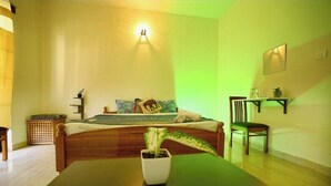 Een slaapkamer met een bed, nachtkastje, stoel en een bijzettafeltje met een plant.
