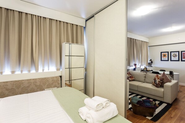 Una habitación de hotel con cama, sofá, zona de comedor y espejo.