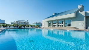 Ein Swimmingpool mit klarem, blauem Wasser, umgeben von Liegestühlen und einem Gebäude mit großen Fenstern.