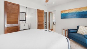 A bedroom with a bed, a ceiling fan, a painting, and a blue sofa. - Makarios Beach Blu (Navarre)