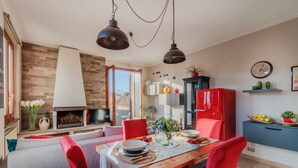 A dining area with a wooden table, red chairs, and a fireplace.