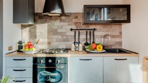 A modern kitchen with a built-in oven, a stove, and a sink. There are cabinets, a countertop, and a backsplash.