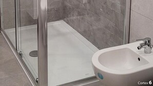 A modern bathroom with a glass-enclosed shower, a white sink, and a stone-textured wall. - Housestation suite H (Palermo)