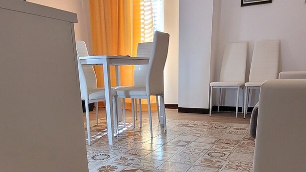 A compact living space with a dining area, a sofa, and a kitchen counter. - Housestation suite H (Palermo)