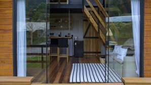 A modern interior with a kitchen area, wooden flooring, and a staircase leading to an upper level. - Refúgio do Vale Cabanas Exclusivas (Bento Gonçalves)