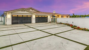 A modern house with two garage doors, a well-maintained driveway, and a landscaped garden. - Rising Sun House: Pool, Spa, GameRoom, PetFriendly! (Palm Springs)