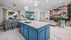 A modern kitchen with a central island, blue cabinets, and pendant lighting. - Rising Sun House: Pool, Spa, GameRoom, PetFriendly! (Palm Springs)