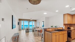 A modern kitchen with wooden cabinets, a central island, and a view to the outside.