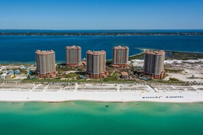A high-rise hotel complex with multiple buildings, a beach, and a body of water. - Portofino Island Resort 2-1902 (Pensacola Beach)
