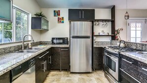 Una cocina moderna con electrodomésticos de acero inoxidable, encimeras de granito y muebles oscuros.