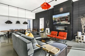 Un salon moderne comprenant un canapé d’angle, un coin repas, une cheminée et un grand écran de télévision.