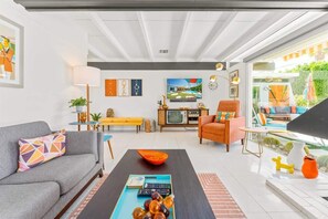 Un salón con sofá, mesa de centro, televisor y ventana con vistas al verde.