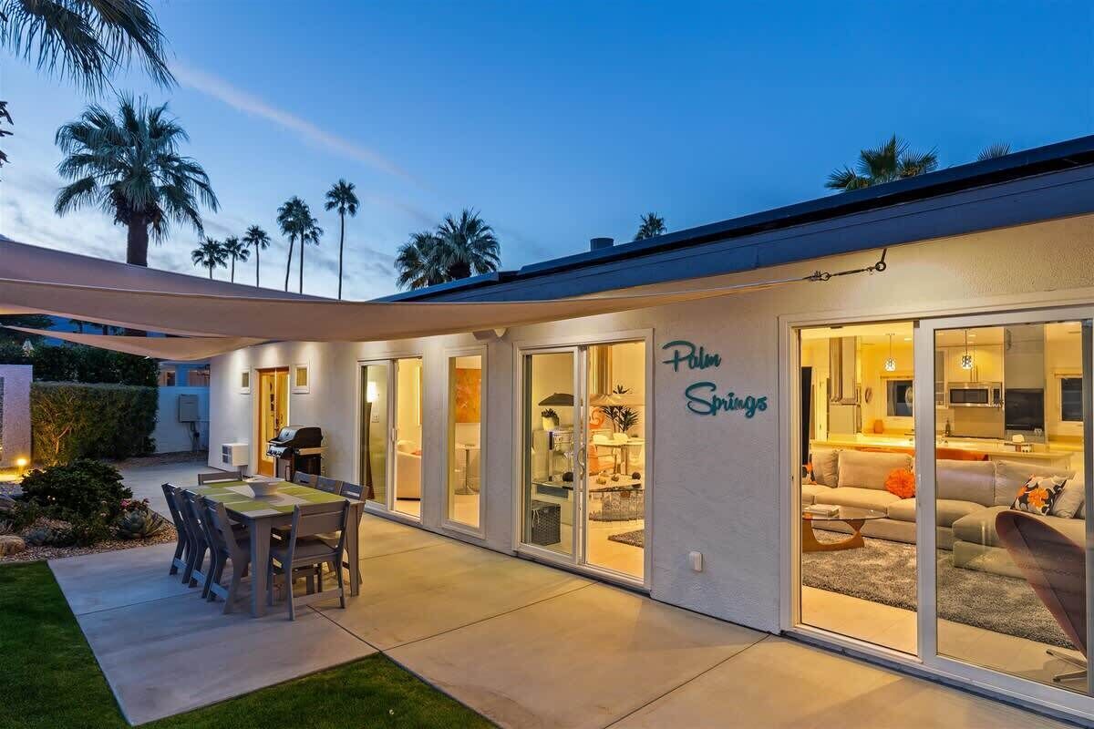 Ett modernt hus med en uteplats, skjutdörrar i glas och en skylt med texten ”Palm Springs”.
