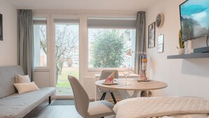 Una habitación moderna con sofá, cama, mesa de comedor y televisor.