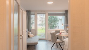 Una habitación con cama, escritorio y silla. Se ve una ventana con cortinas, y una puerta a la izquierda.