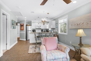 A modern kitchen with a central island, a dining area with chairs, a ceiling fan, and a chandelier. - Sunset Harbor Palms 2-301 (Navarre)