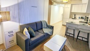 Un espace de vie moderne comprenant un canapé, une table basse et un coin cuisine.