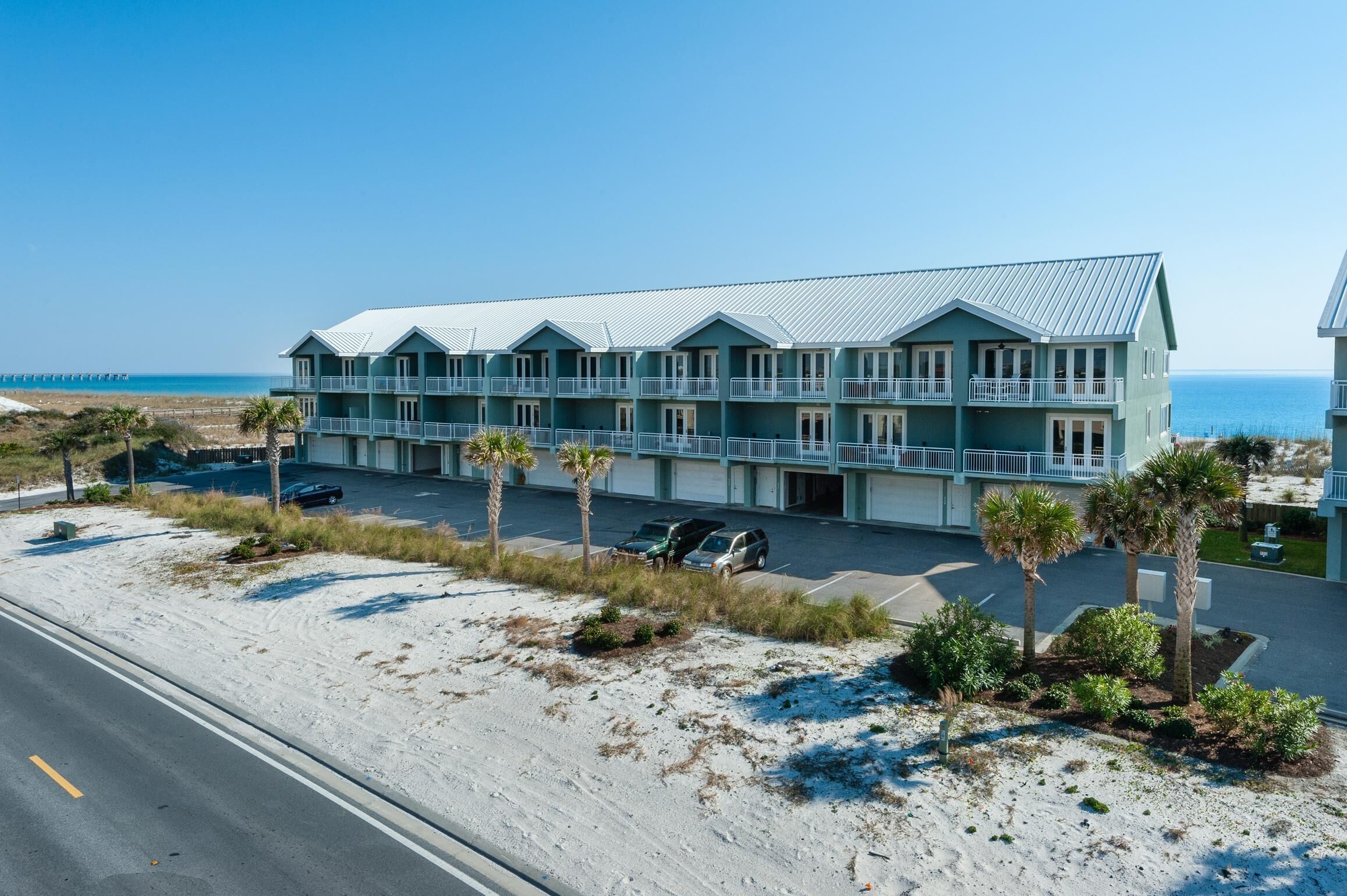 Un hôtel situé en bord de mer, doté de nombreux balcons, d’un parking et d’une plage de sable.