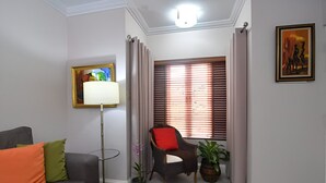 A living room with a grey sofa, a floor lamp, a chair with a red cushion, and a window with blinds. - Secluded Ravinia Gem in Kingston  (Kingston)