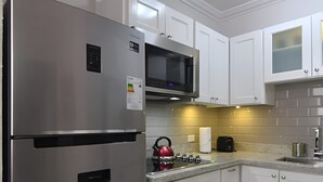 A modern kitchen with white cabinets, stainless steel appliances, and a tiled backsplash. - Secluded Ravinia Gem in Kingston  (Kingston)