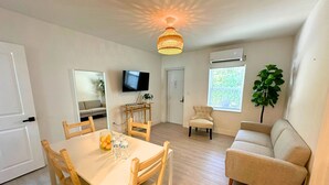 Un salon moderne comprenant un coin repas, un téléviseur fixé au mur et une grande fenêtre offrant une belle vue.