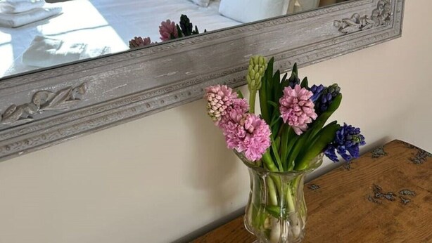A bedroom with a bed, a large mirror, and a vase with flowers on a wooden dresser. - A family and dog friendly haven, The Hayloft. (Sweffling)