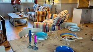 A cozy living room with a striped sofa, a dining table set for two, and a kitchen in the background. - A family and dog friendly haven, The Hayloft. (Sweffling)