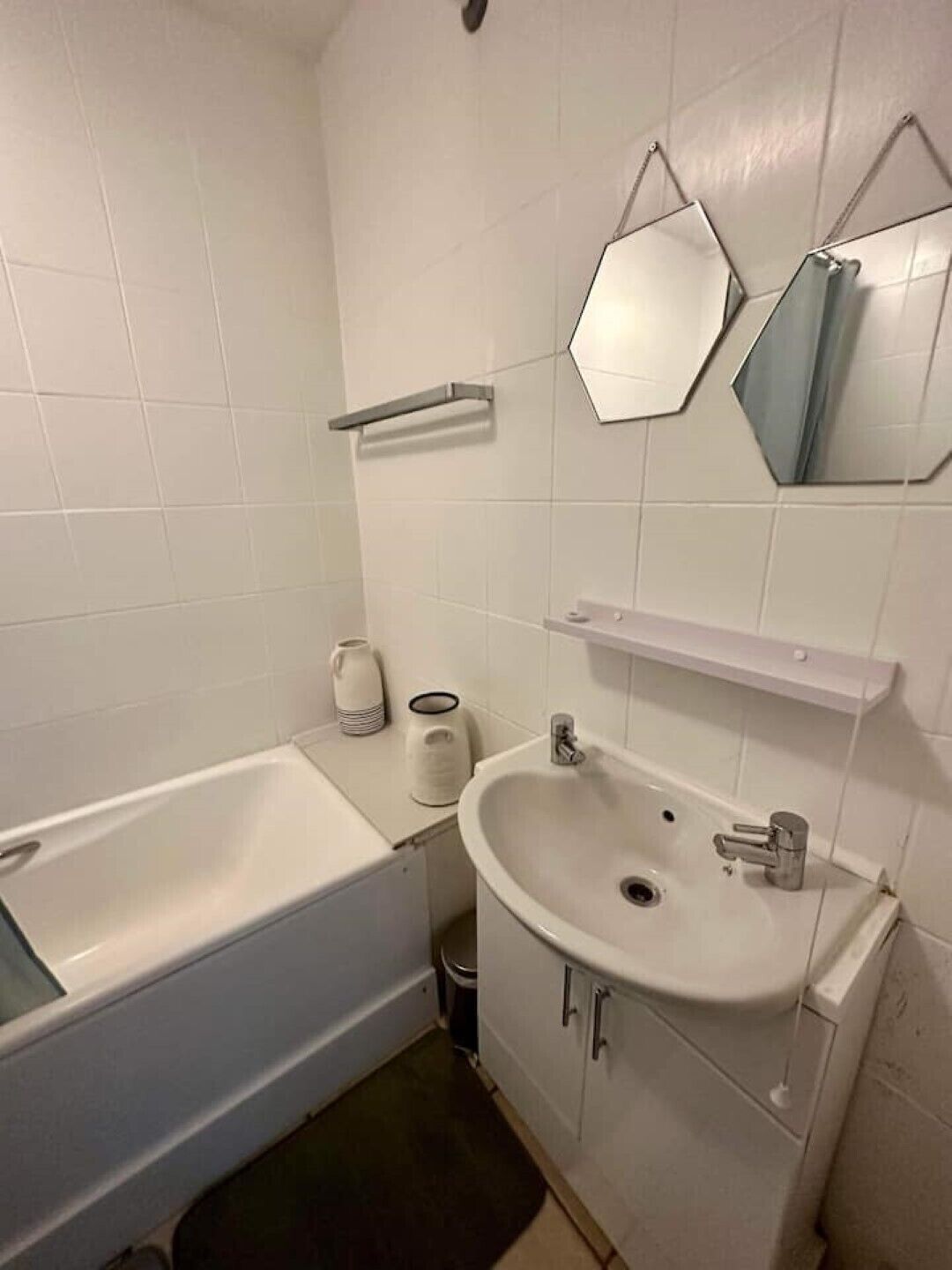 A bathroom with a bathtub, sink, and two mirrors.