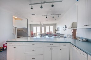 Una cocina moderna con armarios blancos, una isla central y un comedor con sillas.