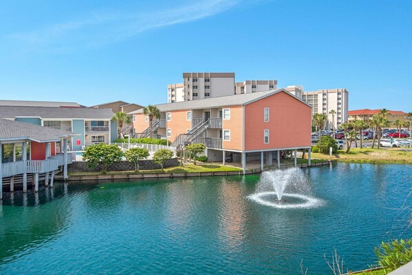 A waterfront property with a dock, a building with a red facade, and a fountain.