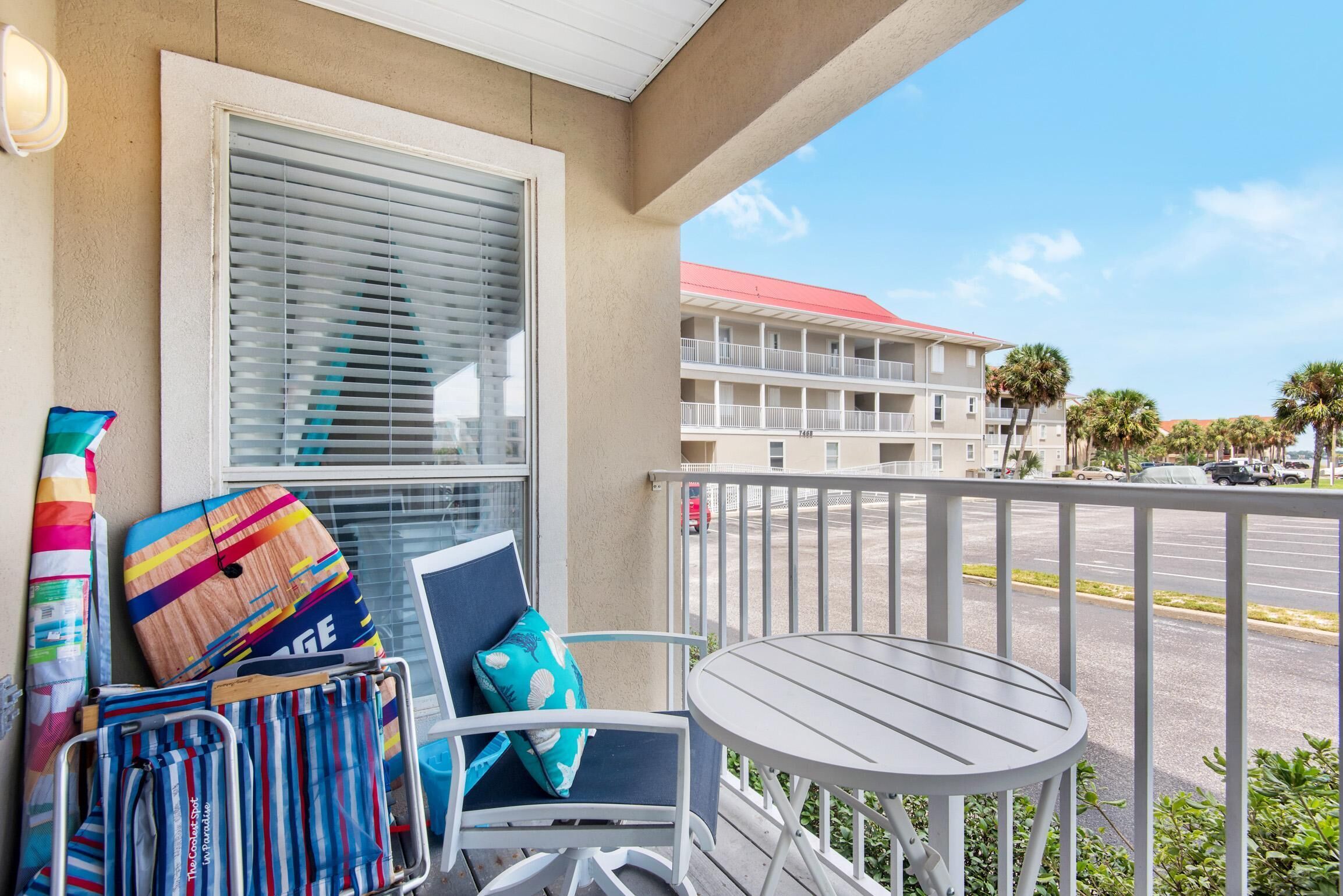 A balcony with a chair, a small table, and a window with blinds.