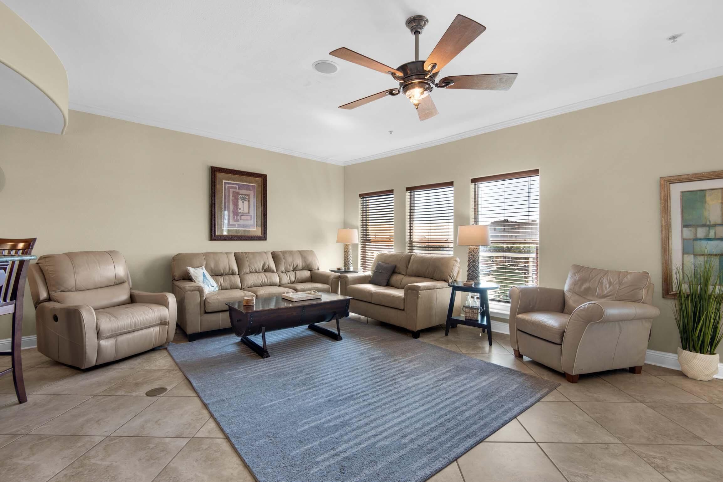 A living room with beige sofas, a coffee table, and a ceiling fan.