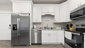 A modern kitchen with white cabinetry, stainless steel appliances, and a granite countertop. - Fun in the Sun 2 Bed Apt. (Biloxi)