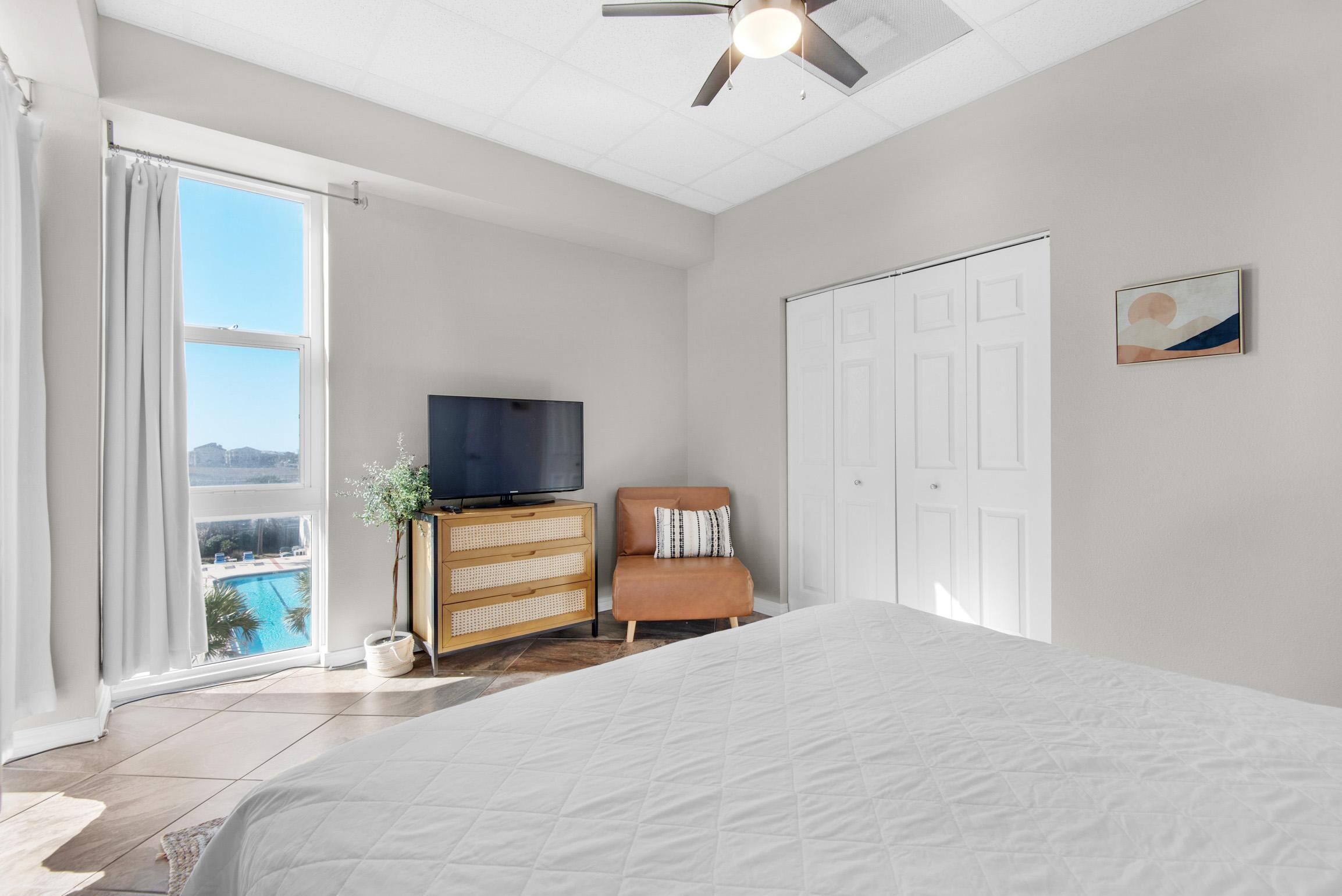 Un dormitorio con cama, televisión, cómoda y vistas a una piscina.