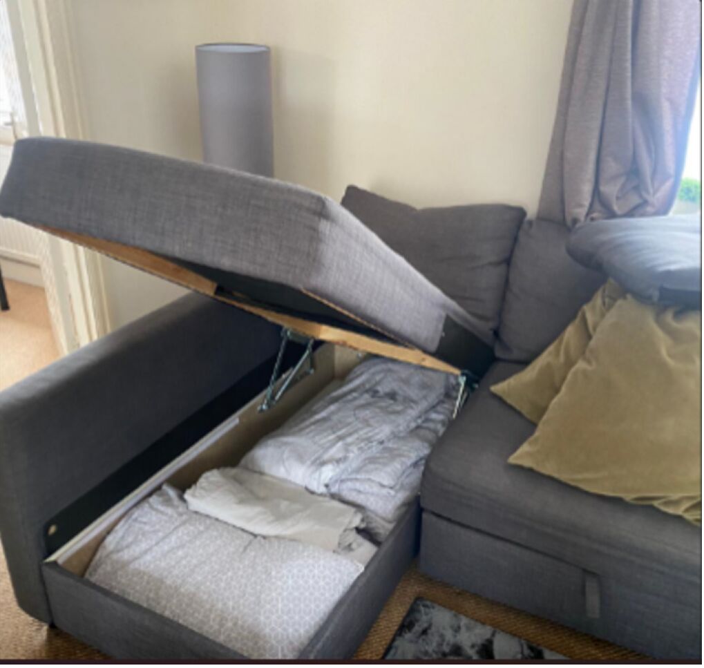 A compact living space with a sofa bed, a small table, and a lamp.