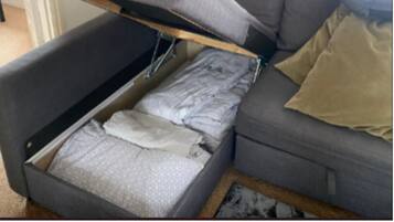 A compact living space with a sofa bed, a small table, and a lamp.