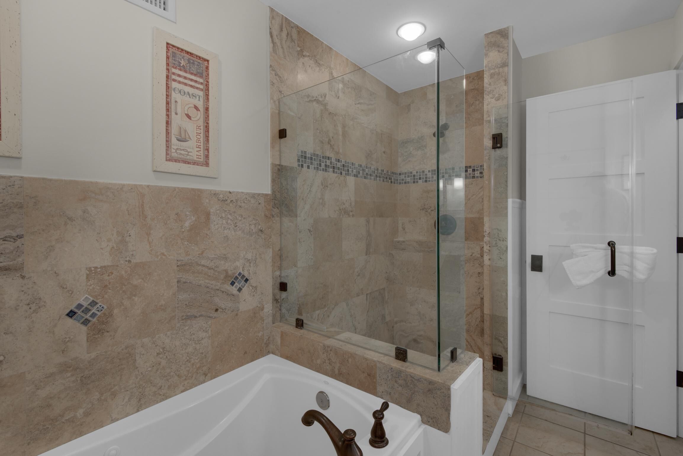 A modern bathroom with a glass-enclosed shower, a white bathtub, and a tiled shower area.