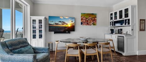 Un comedor con una mesa redonda de vidrio, sillas de madera y un sofá azul estampado.