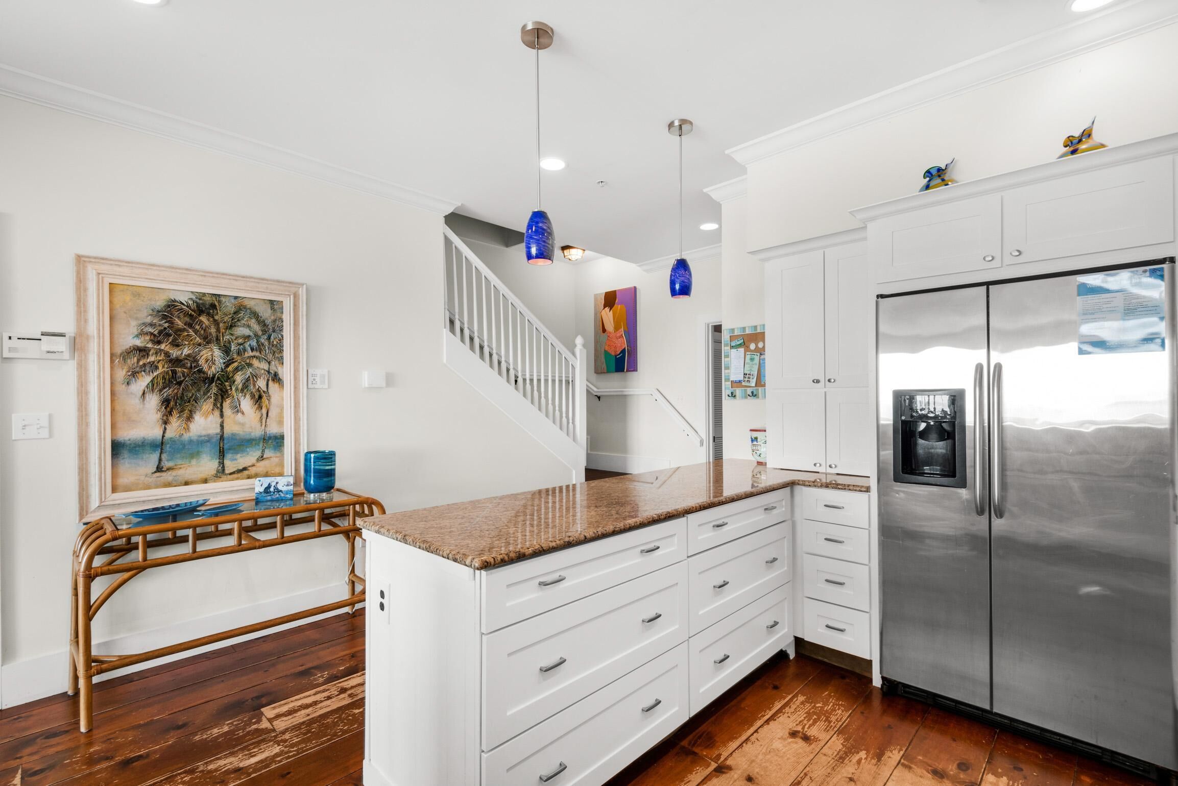 A kitchen with white cabinets, a stainless steel refrigerator, and a wooden dining table.
