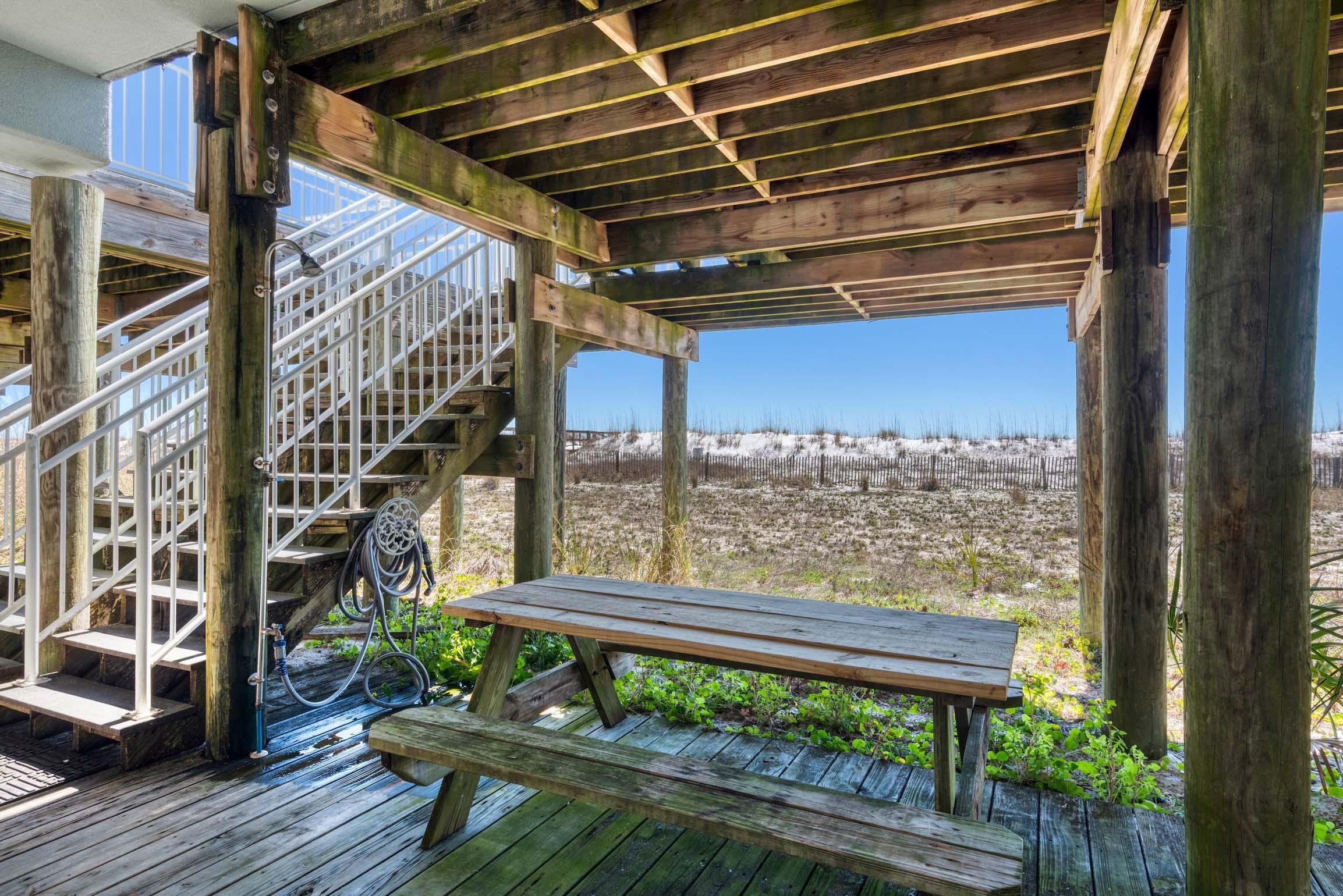 A wooden deck with a metal staircase and a picnic table.