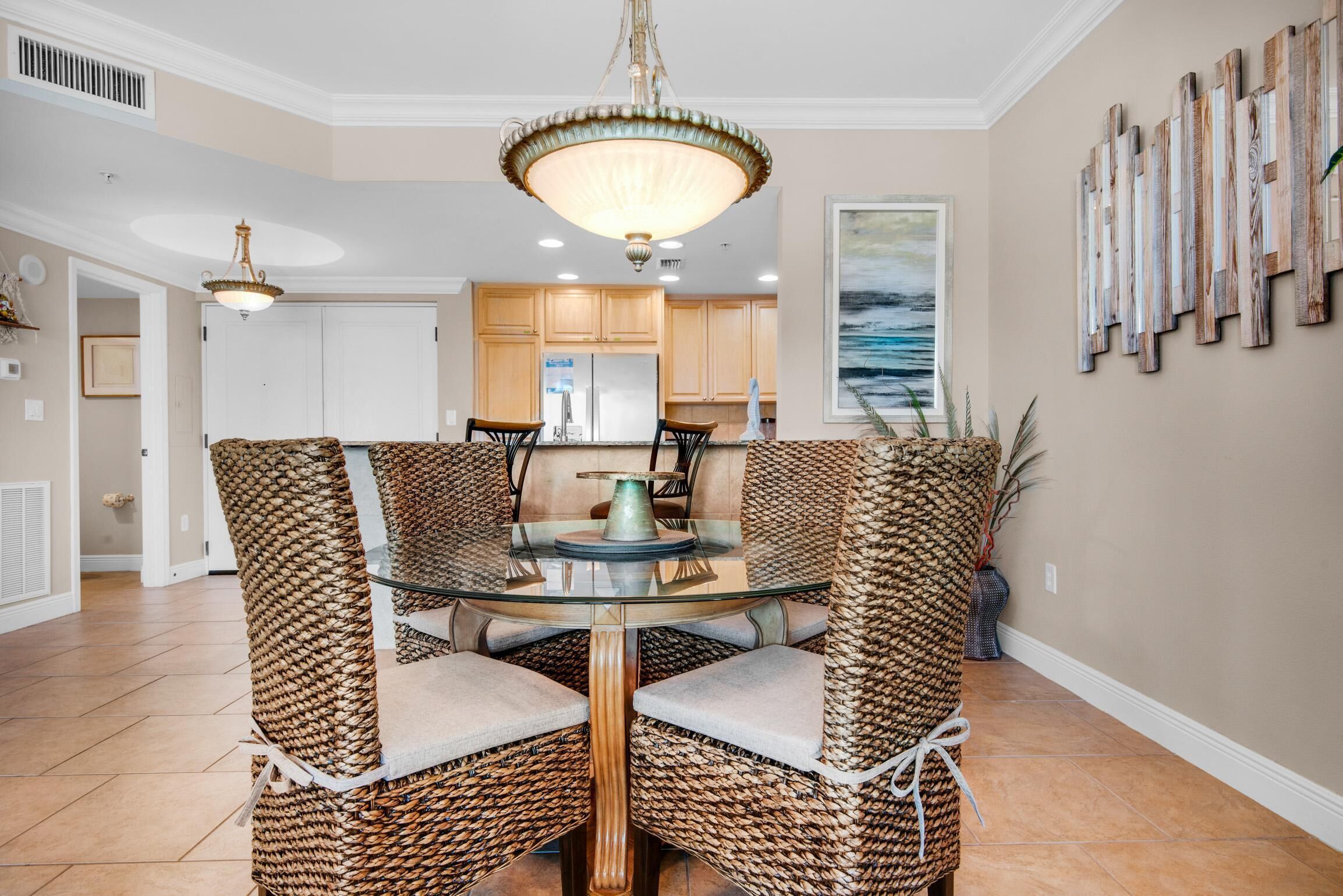 A dining area with wicker chairs, a glass table, and a chandelier.