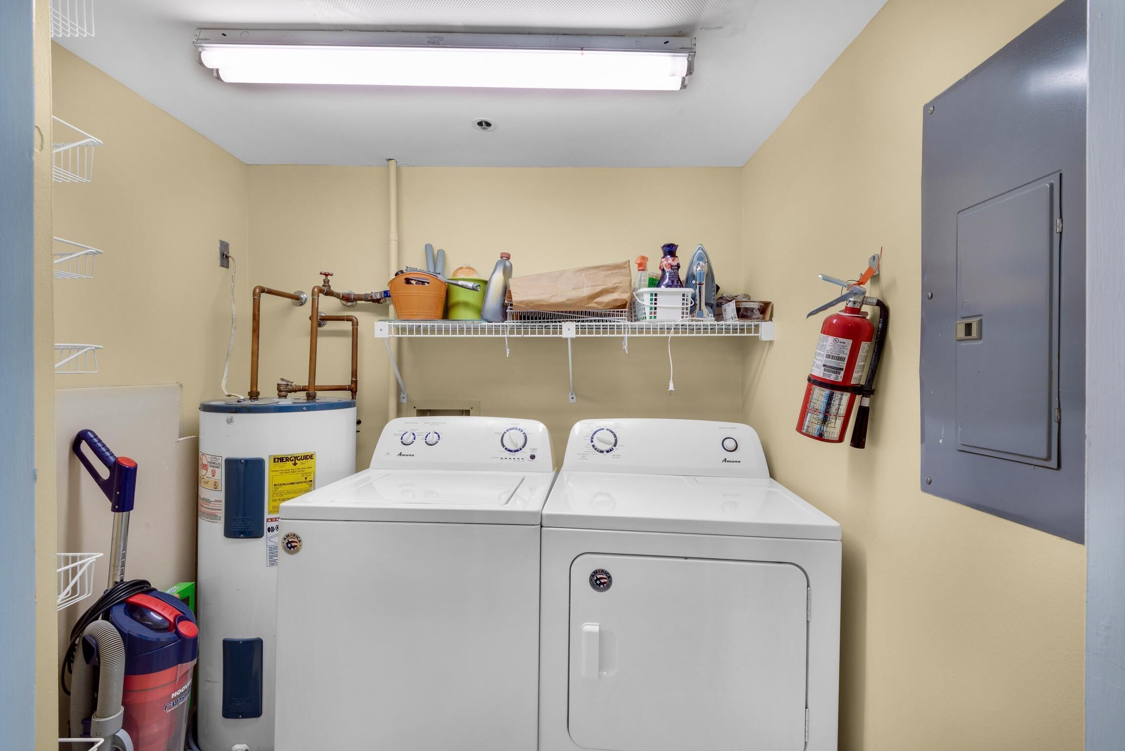 A laundry room with two front-loading washers, a water heater, a fire extinguisher, and a ceiling light.