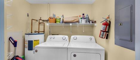 A laundry room with two front-loading washers, a water heater, a fire extinguisher, and a ceiling light.