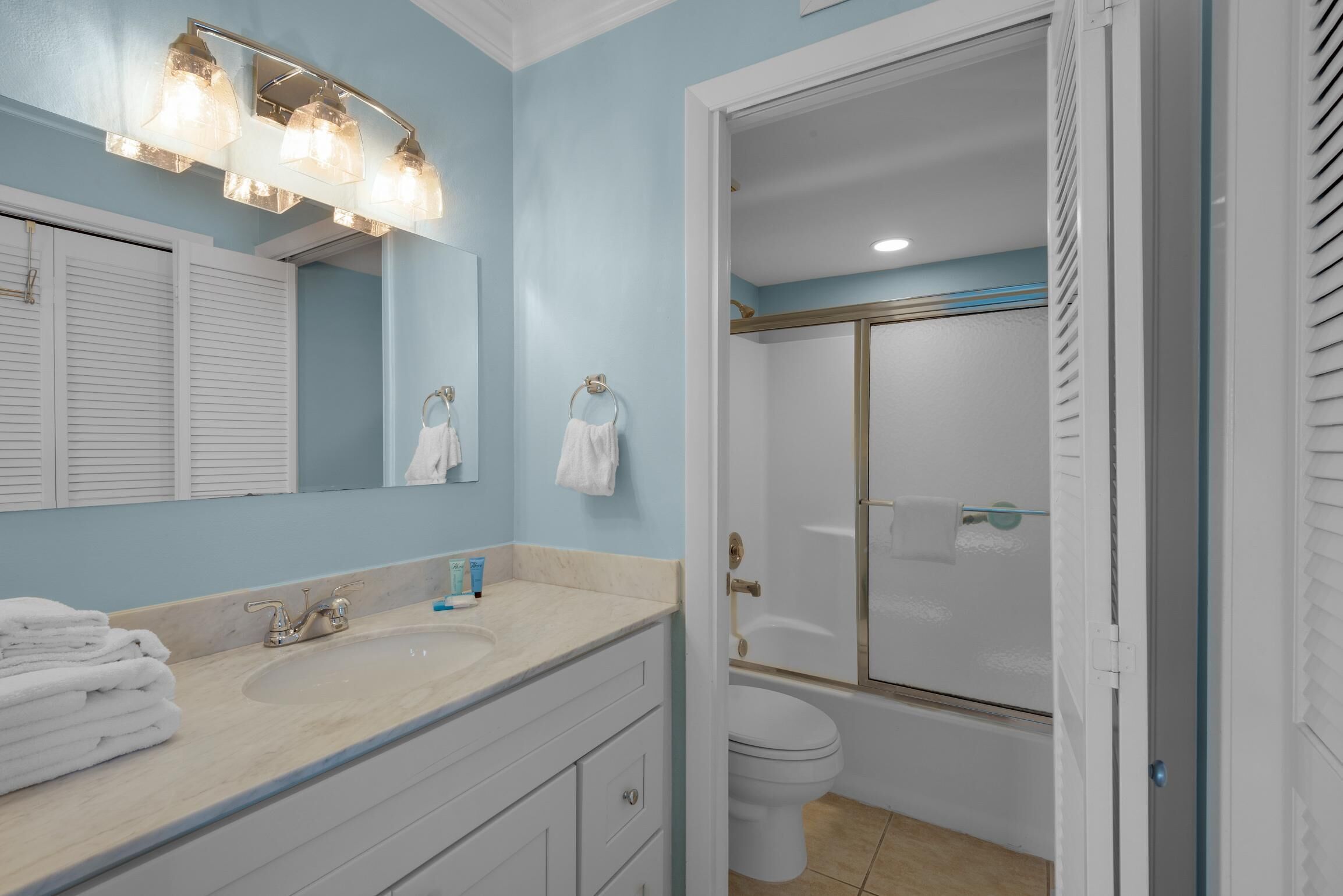 A bathroom with a sink, mirror, and a shower area.